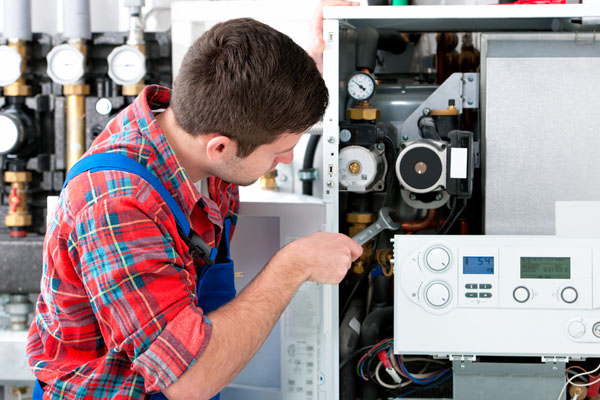 HVAC technician inspecting and repairing boiler controls in Tempe