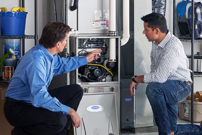 65df8c11f3e4c468cbd351a5_furnace repair vs replacement – Copy HVAC technician explaining furnace repair and maintenance to a homeowner in Tempe, AZ